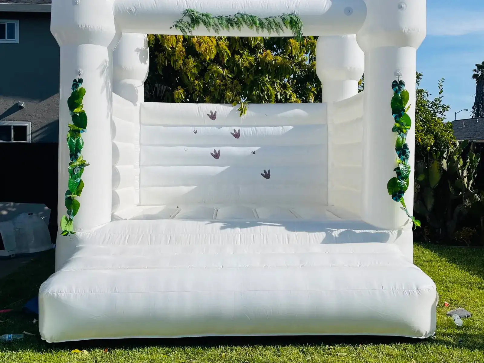 White castle-style bounce house decorated with greenery on a lawn